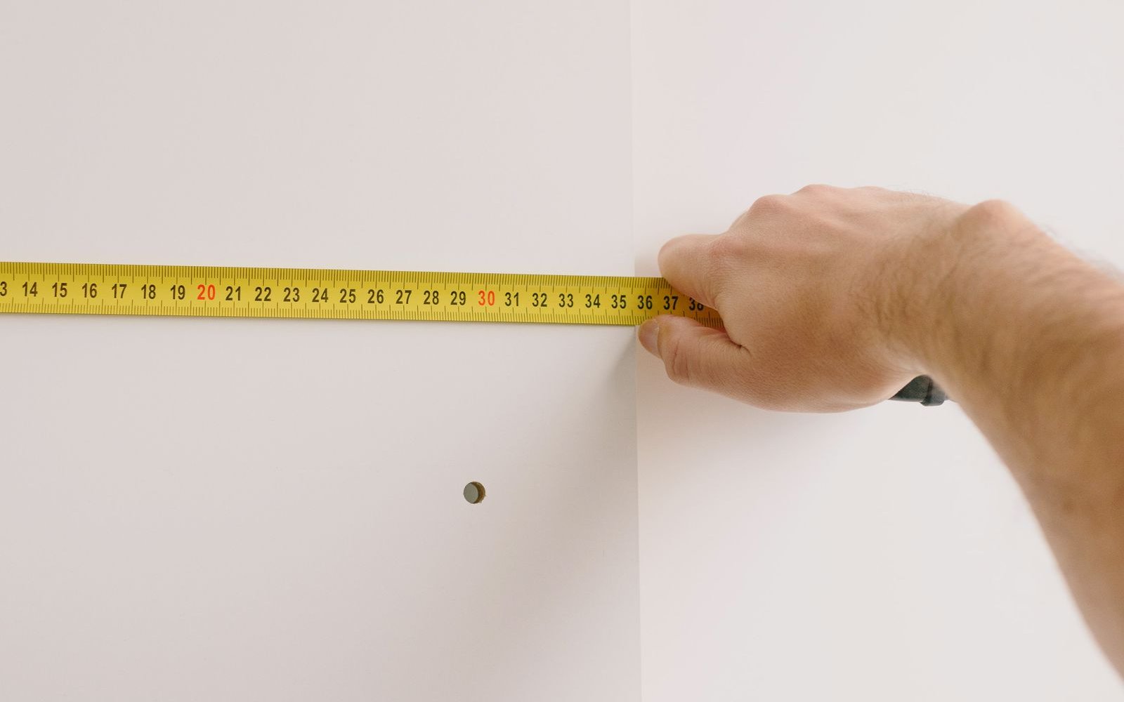 Maler misst mit dem Zollstock eine Wand auf, Grundlage für die Rechnung